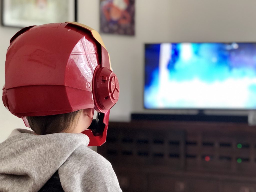 Child dressed as iron man watching television