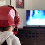 Child dressed as iron man watching television