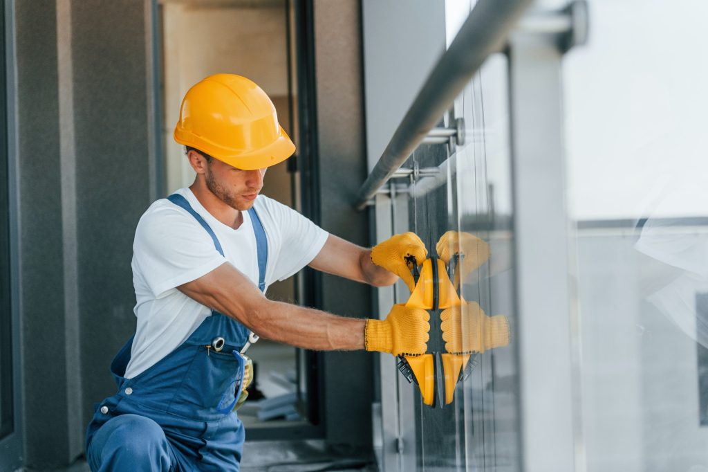 Installation of windows. Young man working in uniform at construction at daytime