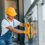 Installation of windows. Young man working in uniform at construction at daytime