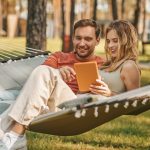 Young beautiful couple with tablet on hammock