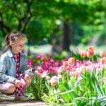 Little adorable girl with flowers in tulips garden