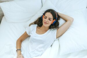 Young woman sleeping in bed at home with headphones